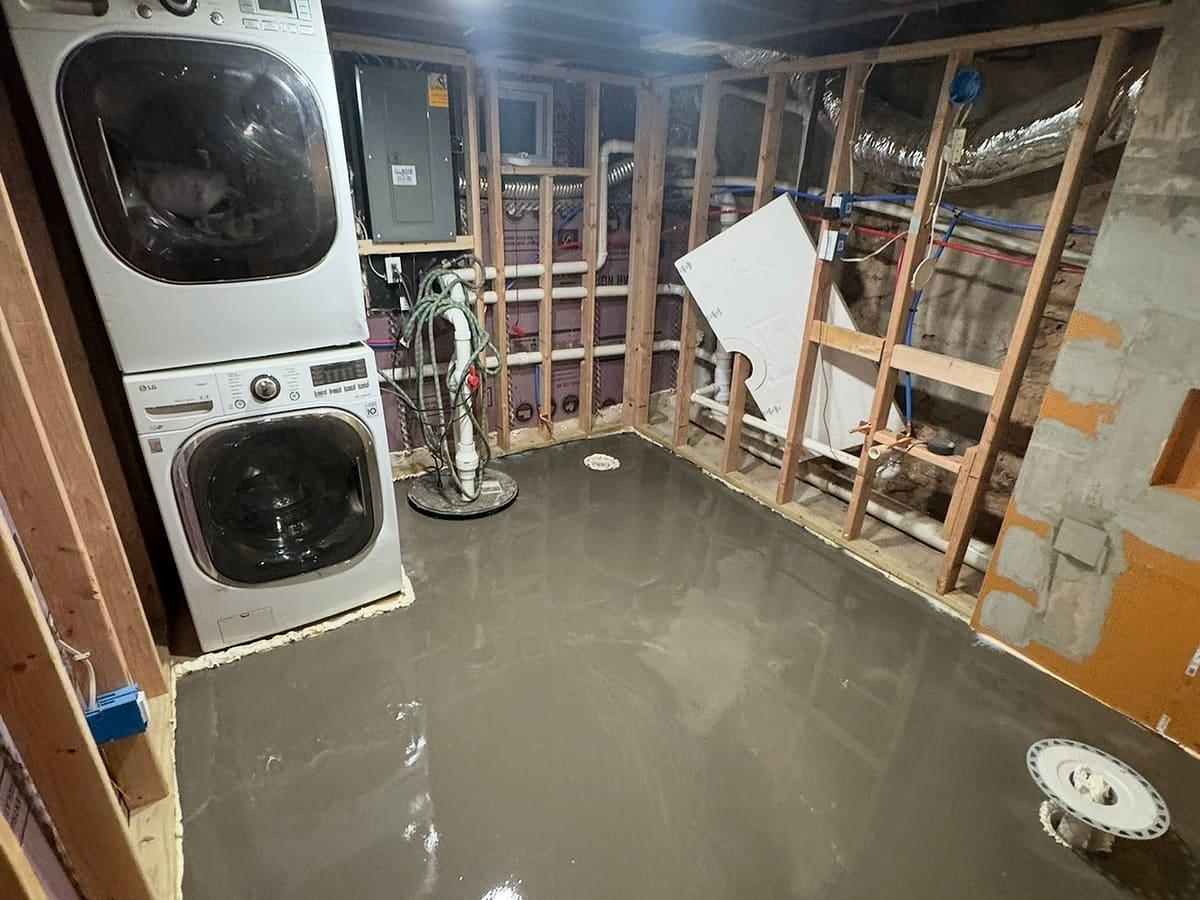 Gutted basement with open framing and a stacked washer and dryer