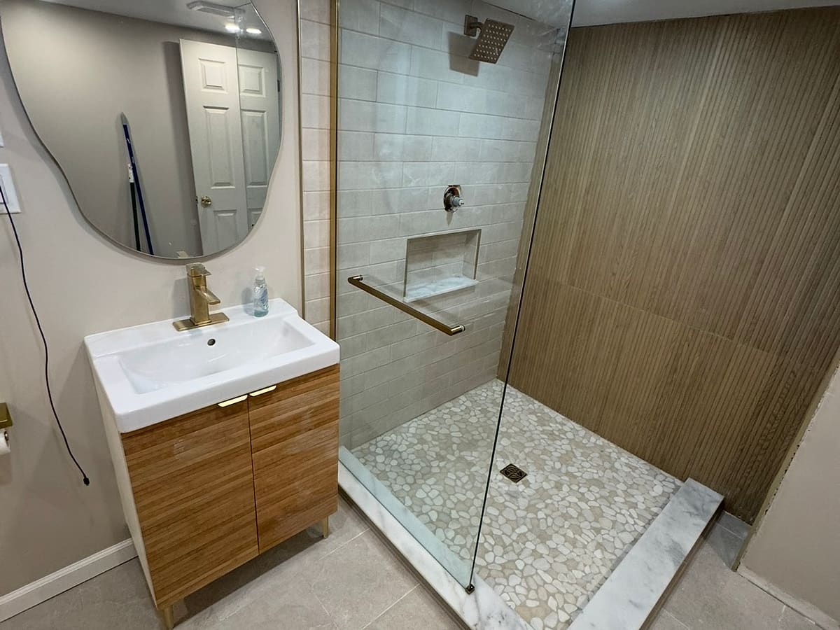 Finished tile shower with niche, pebble floor and glass panel