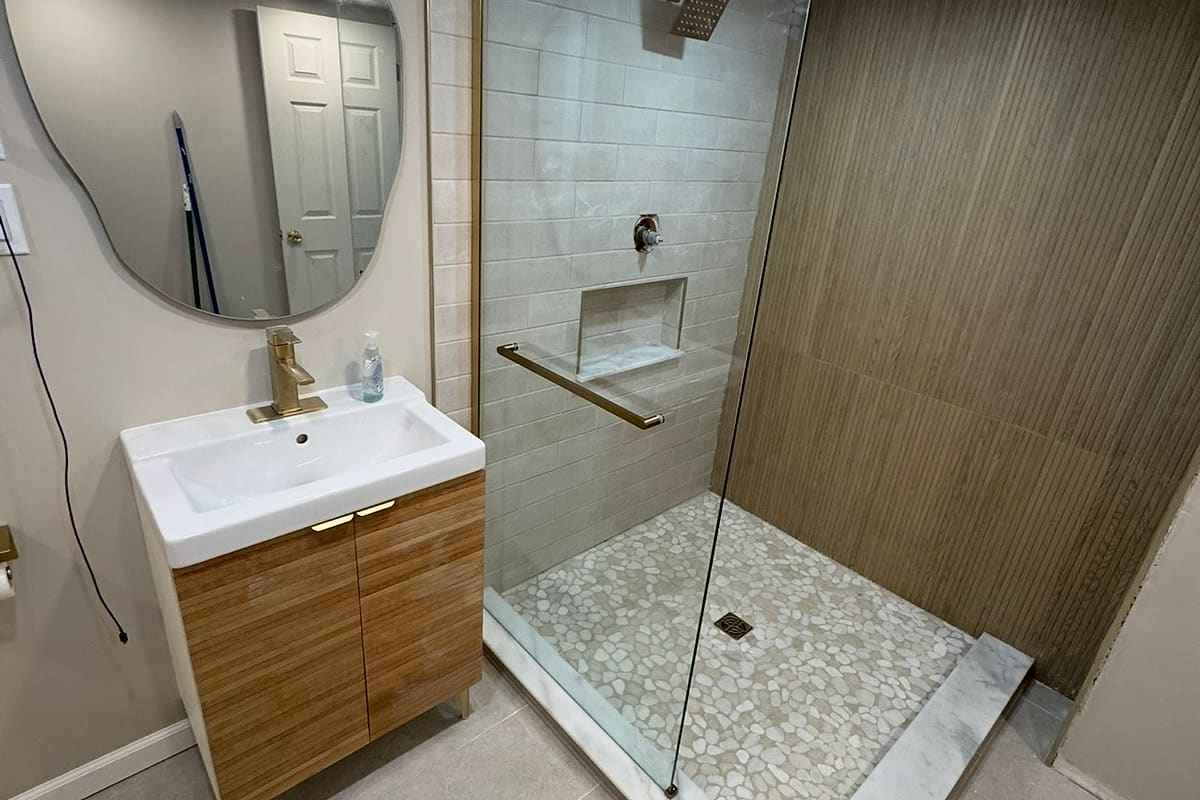 Finished tile shower with a glass panel, niche and new wood vanity